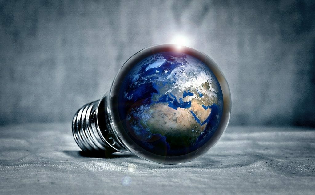 A light bulb with the earth globe inside it, illuminating brightly on a textured self-storage surface.