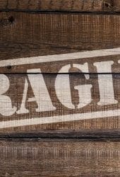 Wooden crate with the word "fragile" stenciled in white across the front, ideal for storing.