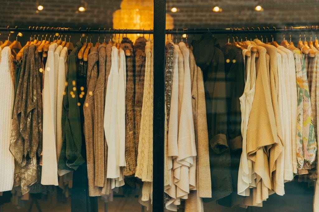 Rack of various clothes seen through a shop window, reflecting warm interior lighting and suggesting ideas for storing.