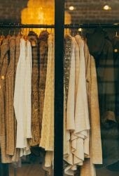 Rack of various clothes seen through a shop window, reflecting warm interior lighting and suggesting ideas for storing.