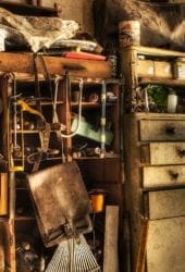 A cluttered workshop with various tools, drawers, and old furniture designated for self storage bathed in warm light.