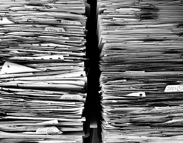 Black and white image of two densely packed piles of documents and files, showing visible labels with dates and codes, ideal for storing in self storage.