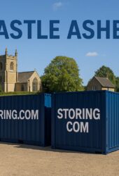 Two blue storage containers labeled "STORING.COM" sit on a gravel lot with a church and trees in the background. The text "CASTLE ASHBY" appears at the top of the image.